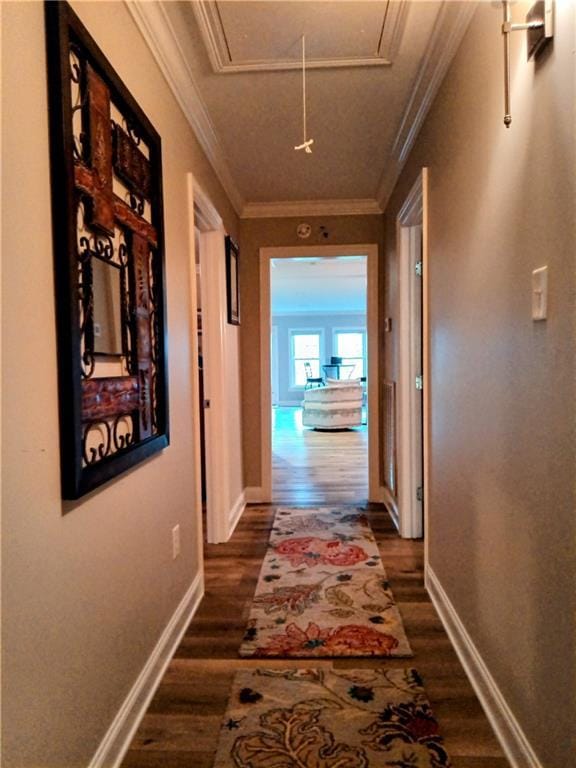 hall featuring baseboards, dark wood finished floors, attic access, and crown molding