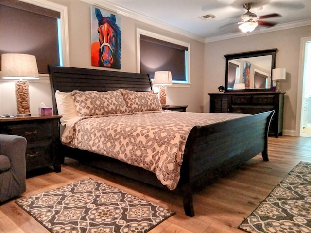 bedroom with ornamental molding, visible vents, and wood finished floors