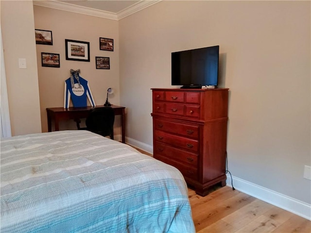 bedroom featuring baseboards, crown molding, and light wood finished floors