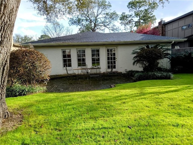 rear view of property with brick siding, a lawn, and a patio