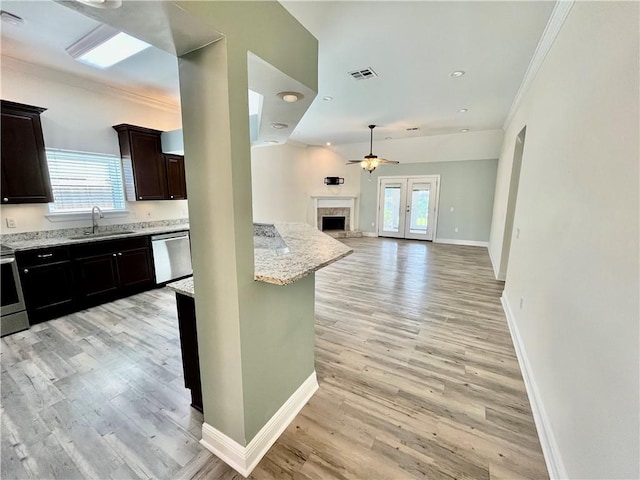 kitchen with crown molding, a fireplace, light wood finished floors, stainless steel appliances, and visible vents