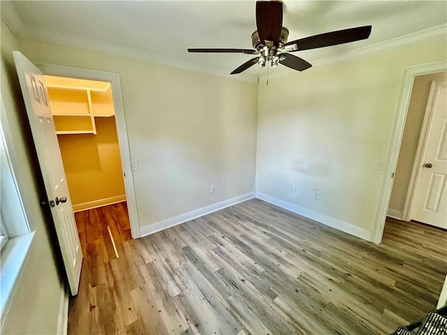 unfurnished bedroom with a ceiling fan, crown molding, light wood-style flooring, and baseboards