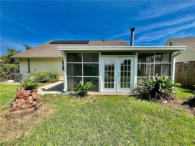 rear view of house featuring a sunroom, a yard, fence, and solar panels