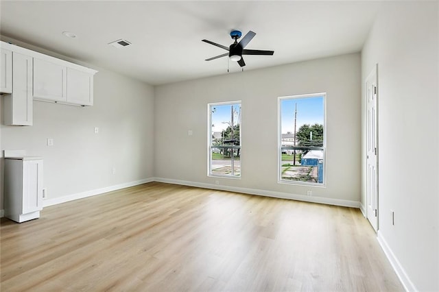 unfurnished living room with a ceiling fan, visible vents, light wood-style flooring, and baseboards