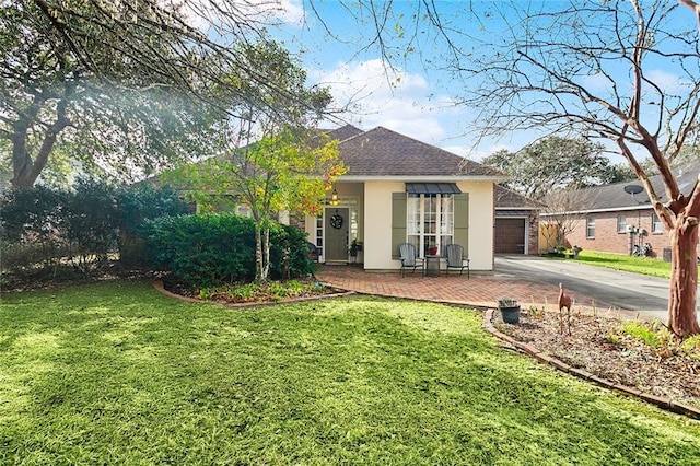 rear view of house with a garage, a shingled roof, concrete driveway, a lawn, and stucco siding