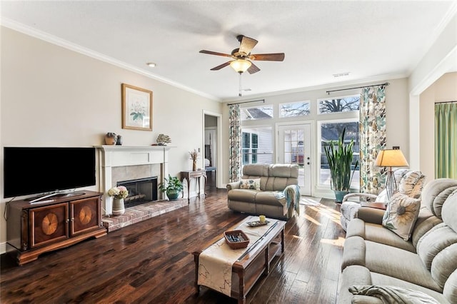 living room with ornamental molding, a fireplace, ceiling fan, and wood finished floors