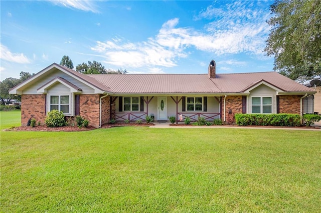 single story home with brick siding, a chimney, metal roof, and a front yard