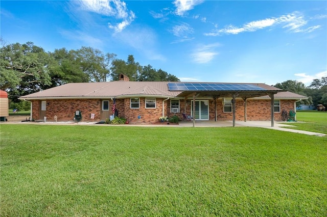 view of front of house featuring brick siding, a chimney, a front lawn, and solar panels