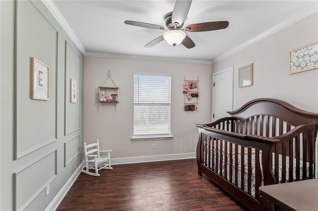 bedroom featuring a crib, baseboards, a ceiling fan, ornamental molding, and wood finished floors