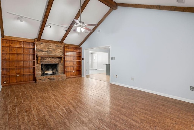 unfurnished living room featuring ceiling fan, a fireplace, wood finished floors, baseboards, and beamed ceiling