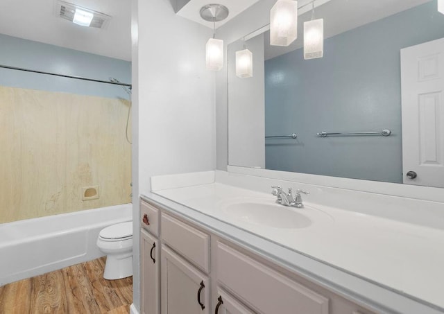 bathroom featuring visible vents, toilet, wood finished floors, vanity, and washtub / shower combination