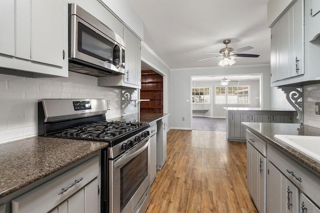 kitchen featuring backsplash, light wood-style flooring, stainless steel appliances, and crown molding