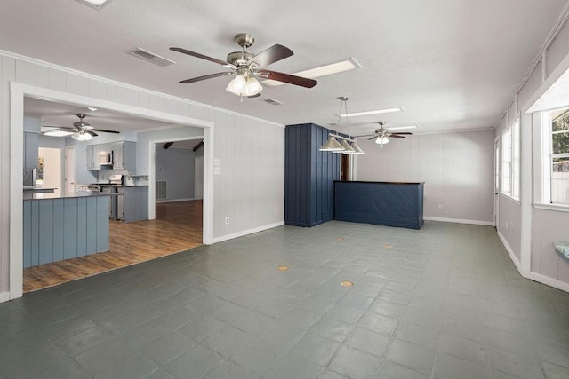 unfurnished living room featuring baseboards, visible vents, crown molding, and tile patterned floors