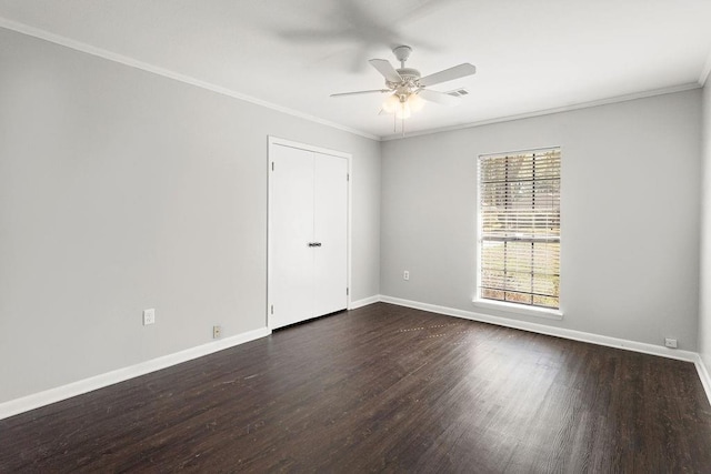 spare room featuring ceiling fan, baseboards, dark wood-type flooring, and crown molding