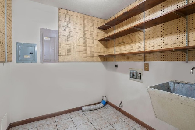 washroom featuring light tile patterned flooring, laundry area, a sink, baseboards, and electric panel