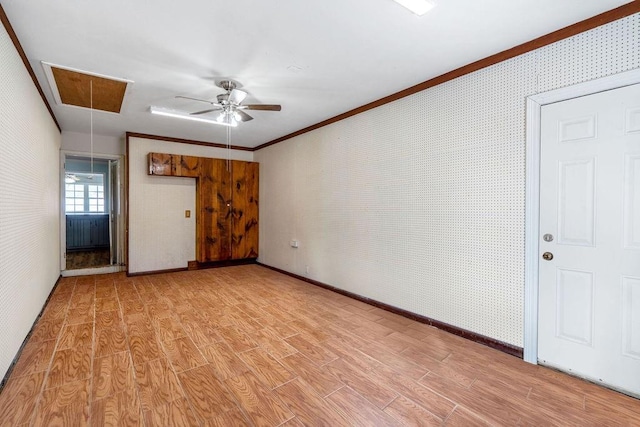 unfurnished living room with attic access, crown molding, light wood-style flooring, and wallpapered walls