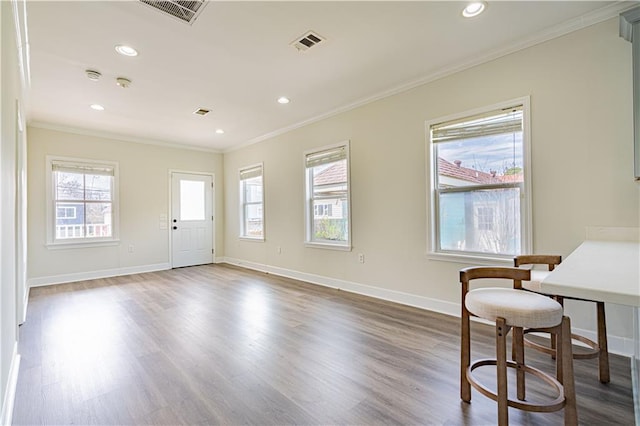 interior space featuring ornamental molding, visible vents, baseboards, and wood finished floors