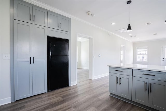 kitchen featuring gray cabinetry, dark wood-style flooring, crown molding, and freestanding refrigerator