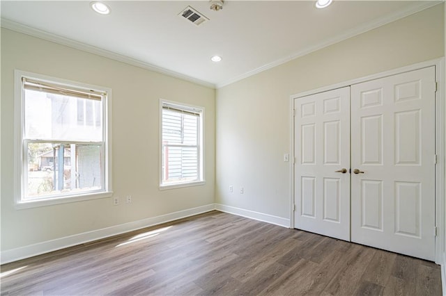 unfurnished bedroom featuring ornamental molding, wood finished floors, visible vents, and baseboards