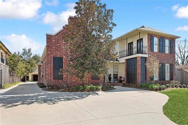 view of front of property with a balcony, concrete driveway, and brick siding