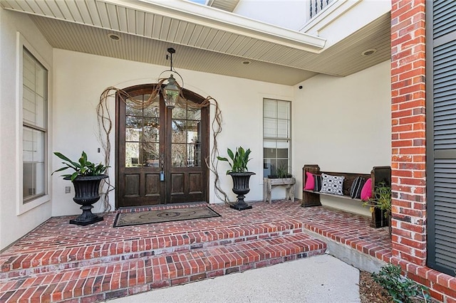 property entrance with french doors, covered porch, and stucco siding