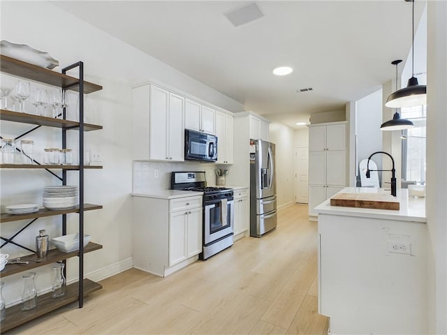 kitchen featuring light wood-type flooring, tasteful backsplash, appliances with stainless steel finishes, and white cabinets