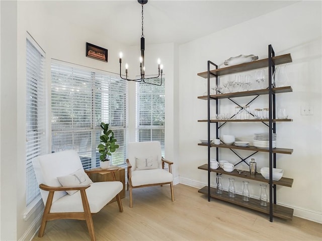 living area with a notable chandelier, baseboards, and light wood-style floors