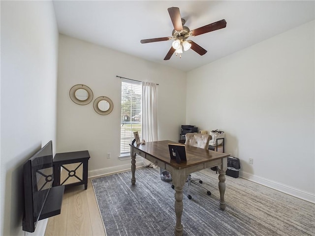 home office featuring light wood-style floors, ceiling fan, and baseboards