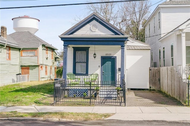 shotgun-style home featuring covered porch and fence