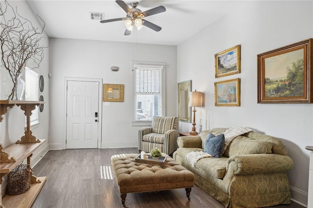 living area featuring a ceiling fan, wood finished floors, visible vents, and baseboards