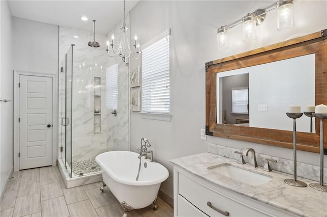 bathroom featuring a marble finish shower, a soaking tub, an inviting chandelier, and vanity