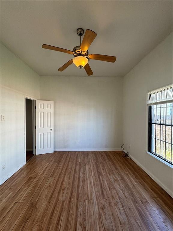 unfurnished room featuring wood finished floors, a ceiling fan, and baseboards