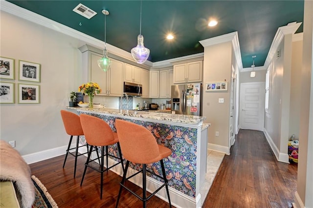 kitchen with appliances with stainless steel finishes, visible vents, a peninsula, and wood finished floors