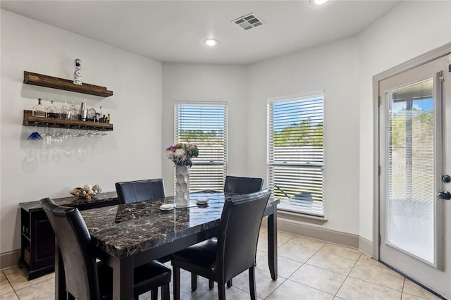 dining area featuring light tile patterned floors, baseboards, visible vents, and a healthy amount of sunlight