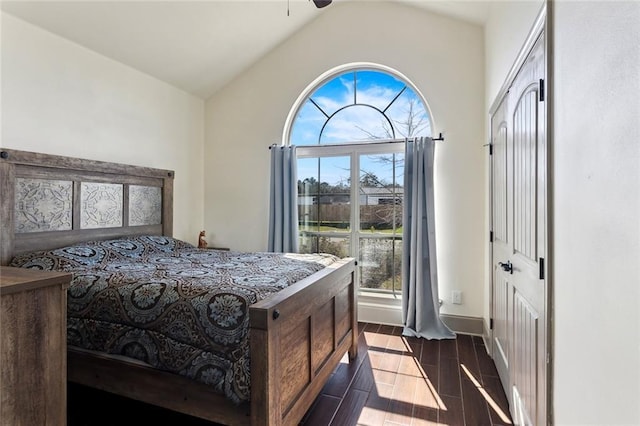 bedroom with dark wood-style floors, lofted ceiling, and baseboards