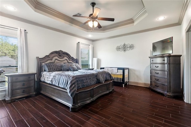 bedroom with wood finish floors, a raised ceiling, visible vents, ornamental molding, and baseboards