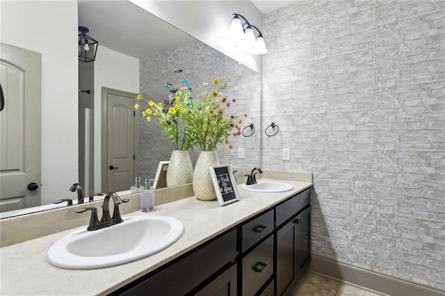 full bath featuring double vanity, baseboards, a sink, and tile patterned floors