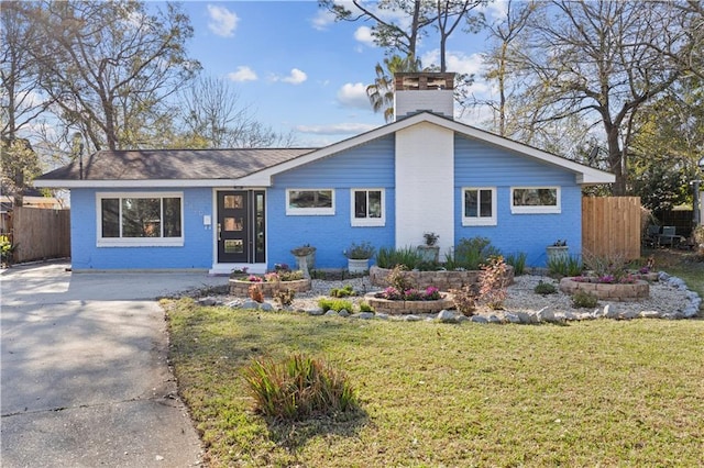 view of front of home featuring concrete driveway, brick siding, a front yard, and fence