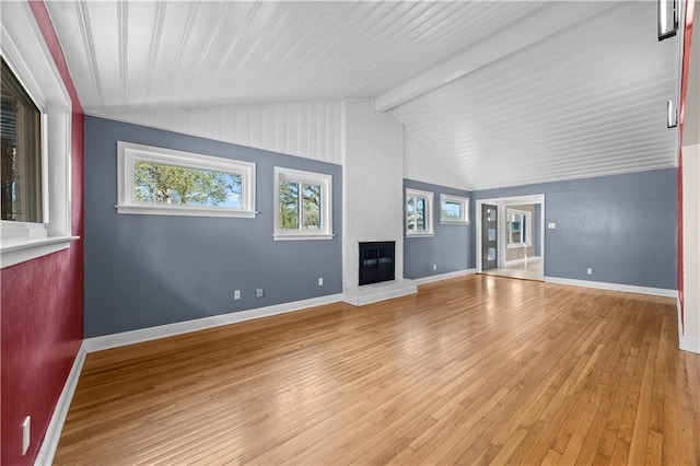 unfurnished living room featuring vaulted ceiling with beams, light wood-type flooring, a fireplace, and baseboards