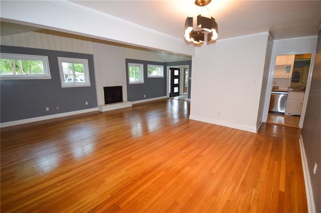 9420 Gerald St, River Ridge, LA 70123 - unfurnished living room featuring a chandelier, light wood-style flooring, crown molding, a brick fireplace, and baseboards