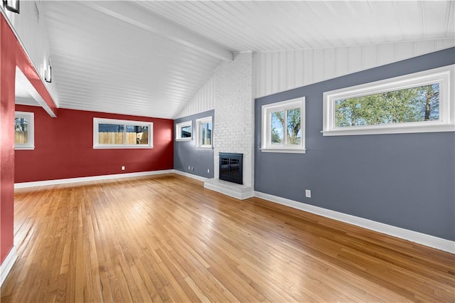 unfurnished living room with lofted ceiling with beams, light wood-style flooring, a fireplace, and baseboards