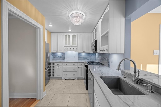 kitchen featuring stainless steel appliances, light stone counters, and a sink