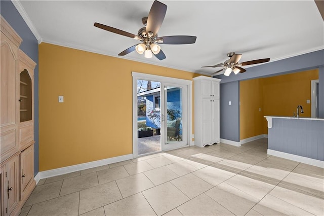 spare room with a sink, light tile patterned floors, baseboards, and crown molding