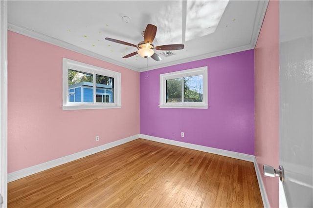 unfurnished room featuring crown molding, visible vents, light wood-style floors, a healthy amount of sunlight, and baseboards