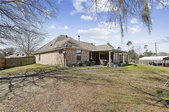 back of property with a yard, brick siding, a patio, and fence