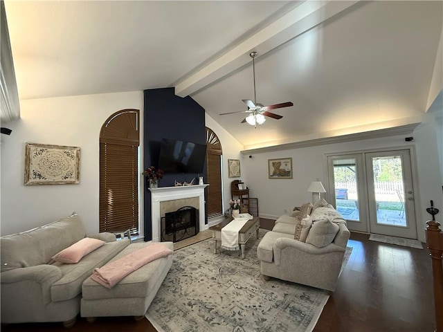 living area featuring vaulted ceiling with beams, a tiled fireplace, wood finished floors, and ceiling fan