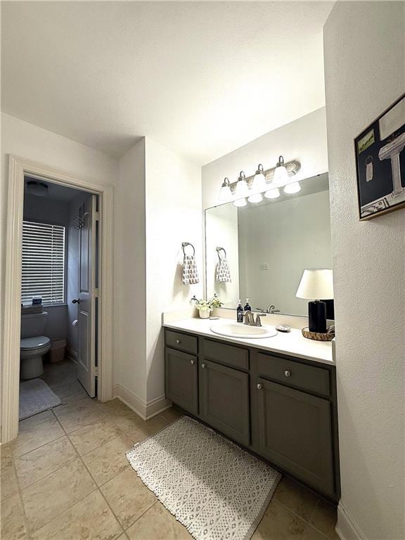 bathroom featuring baseboards, toilet, tile patterned flooring, and vanity
