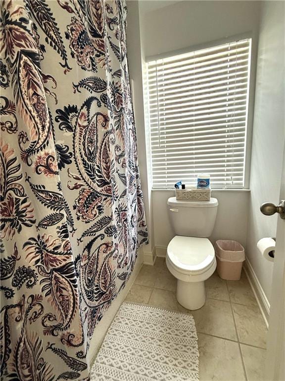 full bathroom featuring baseboards, toilet, tile patterned flooring, and curtained shower