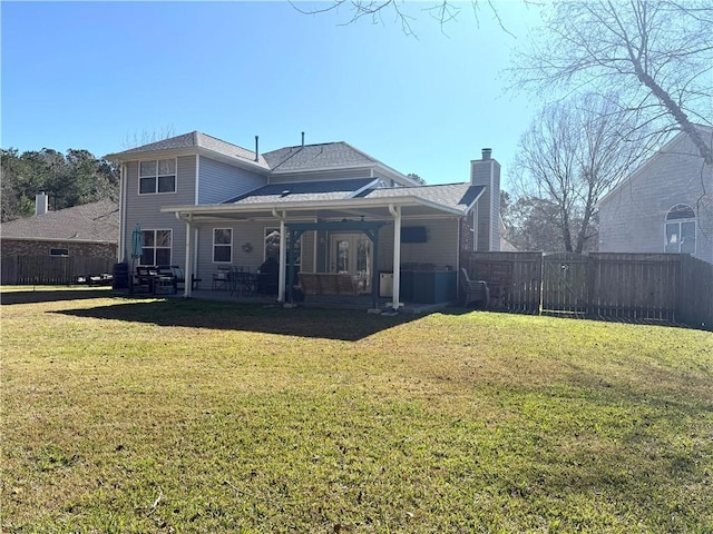 rear view of house featuring a lawn, a chimney, a fenced backyard, and a patio area