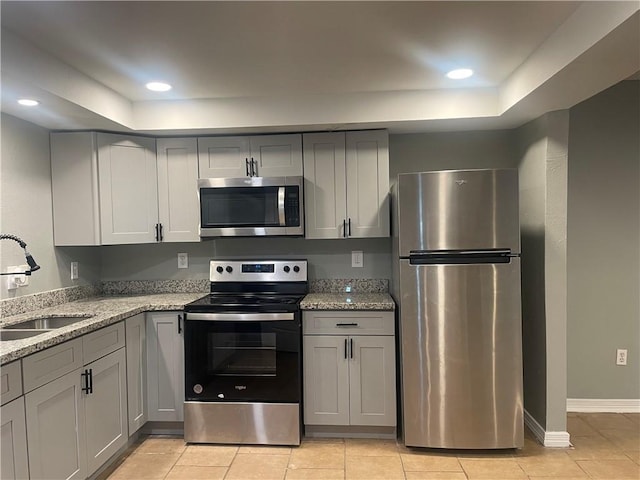 kitchen featuring appliances with stainless steel finishes, a sink, and gray cabinetry